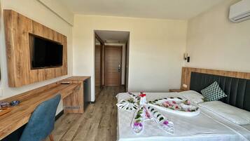 Ein Hotelzimmer mit einem Holztisch, einem Flachbildfernseher, einem Bett mit floralem Bettbezug und einem Kopfteil.
