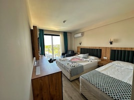 Habitación de hotel con dos camas, un escritorio, una silla y un balcón con vistas.