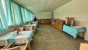 A dining area with tables and chairs, a buffet counter with food items, and a person in uniform.