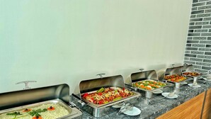 Buffet com diversos pratos, incluindo arroz, vegetais e carnes.