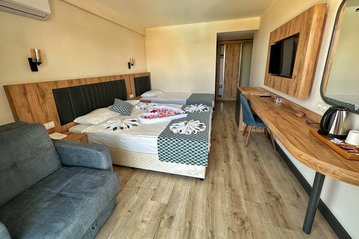 Une chambre d’hôtel équipée d’un lit, d’un bureau, d’une chaise, d’un canapé et d’une télévision.