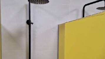 A shower with a black hose and a handheld showerhead mounted on a wall.