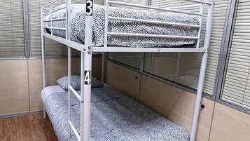 A bunk bed with two levels, numbered 3 and 4, in a room with beige walls and a window with blinds.