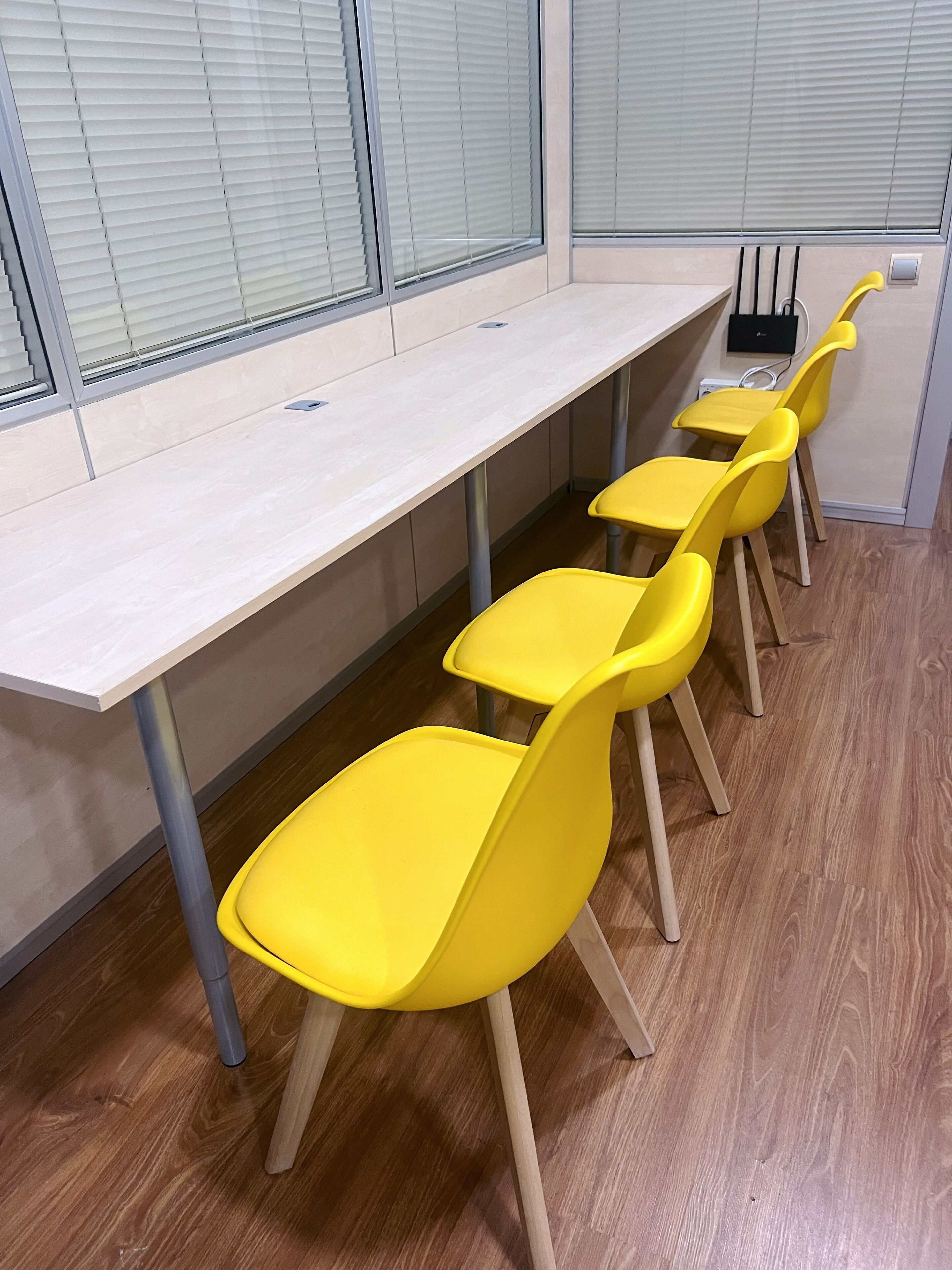 A conference room with a long table and four yellow chairs.