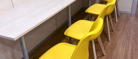 A conference room with a long table and four yellow chairs.