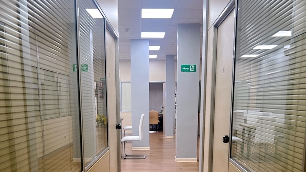 A corridor with glass partitions, wooden flooring, and ceiling lights. - Hostel Acacias (Madrid)