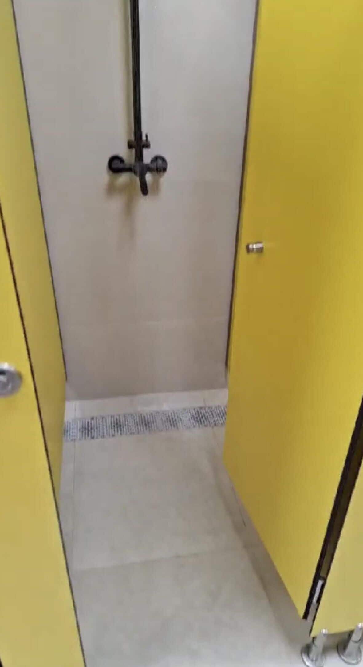 A narrow hallway with yellow doors on either side, leading to a room with a tiled floor.