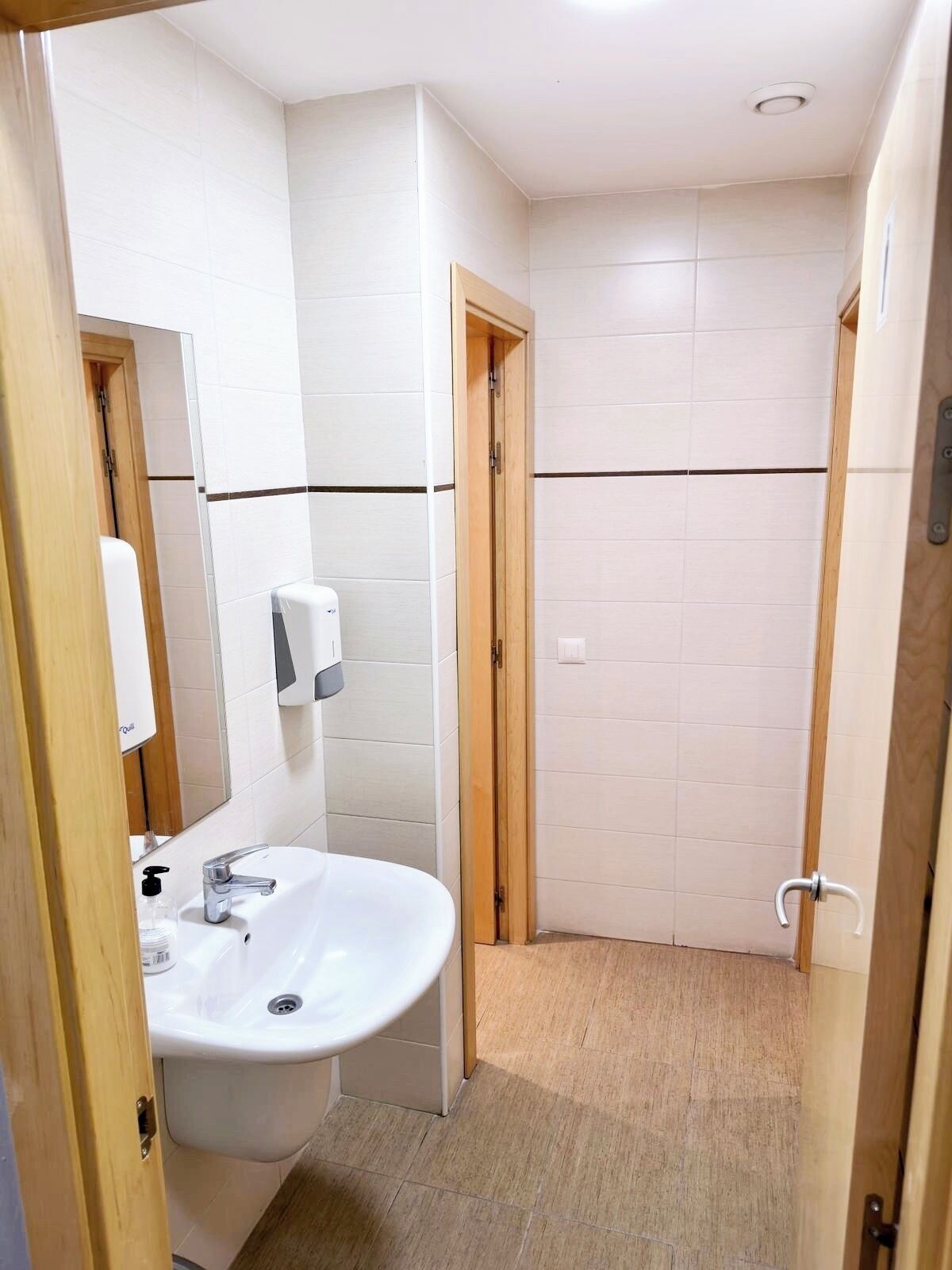 A small bathroom with a sink, mirror, and a towel dispenser.