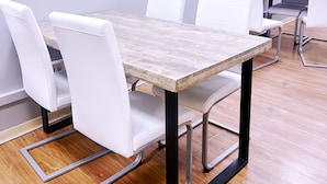 A conference table with white chairs and metal frame legs, set on a wooden floor in a room with white walls. - Hostel Acacias (Madrid)