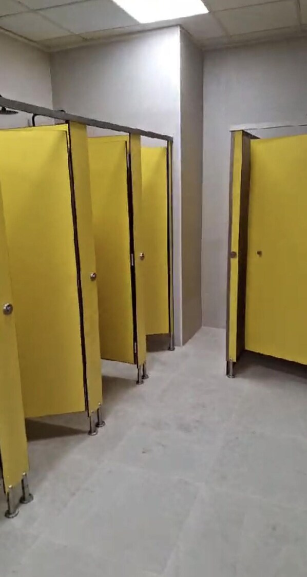 Fila de baños separados en amarillo con suelo de baldosas.