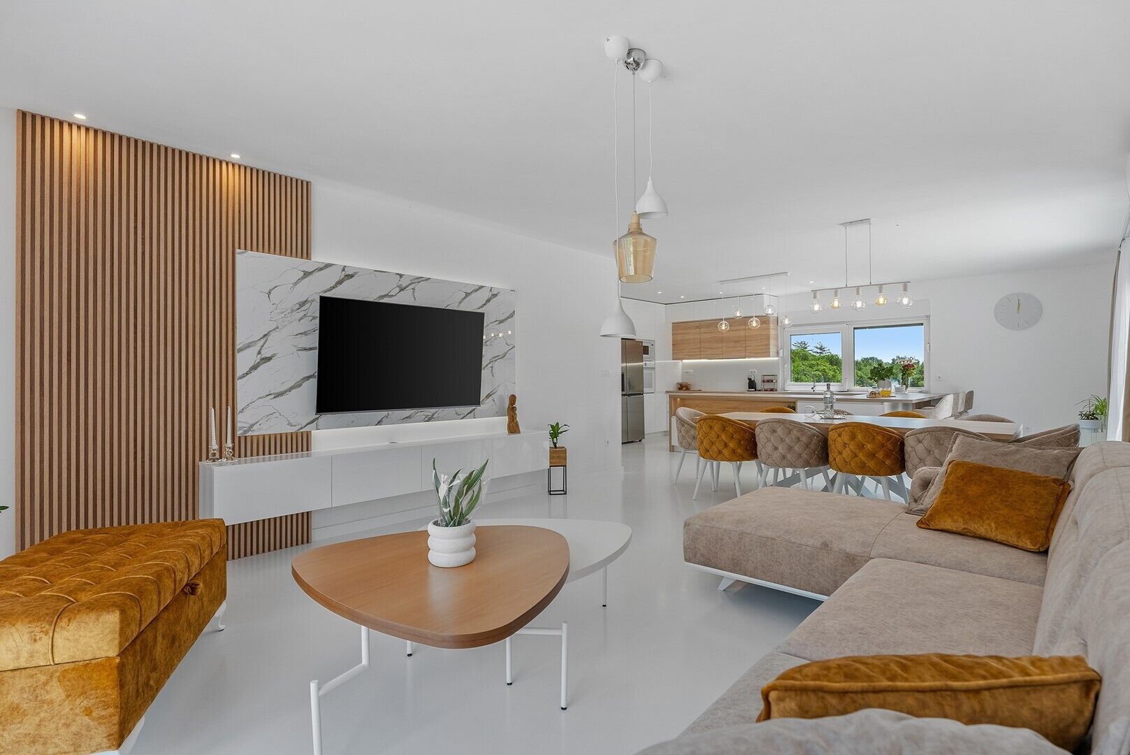 Un salon moderne comprenant un téléviseur, un canapé, une table basse et un coin repas avec des chaises.