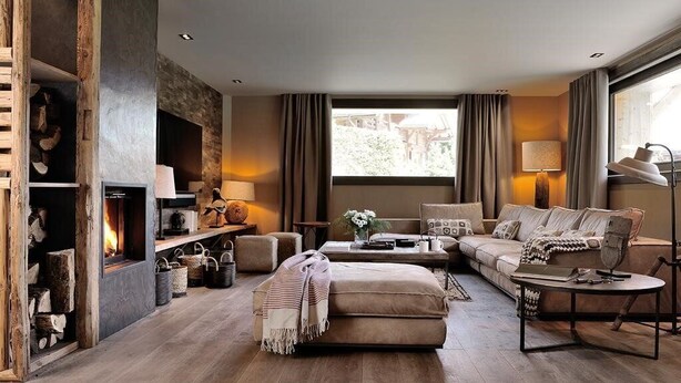 A cozy living room with a fireplace, a sofa, a coffee table, and a lamp. - Chalet Le Prariand (Megève)