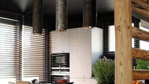 A modern kitchen with a central island, black chairs, and pendant lights. - Chalet Le Prariand (Megève)