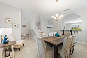 A dining area with a wooden table and chairs, a chandelier, and a staircase in the background. - Resort, Pool, Spa and Fun! (Davenport)