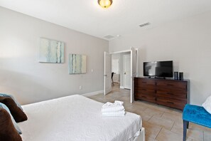 A bedroom with a bed, a dresser, a television, and artwork on the wall. - Resort, Pool, Spa and Fun! (Davenport)