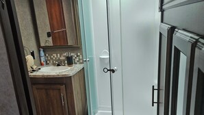 Une salle de bain moderne avec une douche à parois de verre, un meuble-lavabo avec un miroir et des armoires en bois.