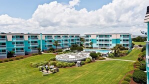 Un hotel de varios pisos con un patio central, piscina al aire libre y jardines bien cuidados.