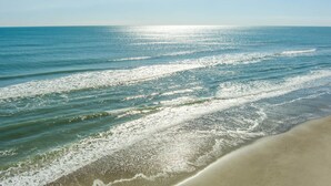 A beach with waves gently lapping onto the shore under a clear sky. - Seacluded Tree House, Oceanfront House in Pine Knoll Shores, NC! (Pine Knoll Shores)