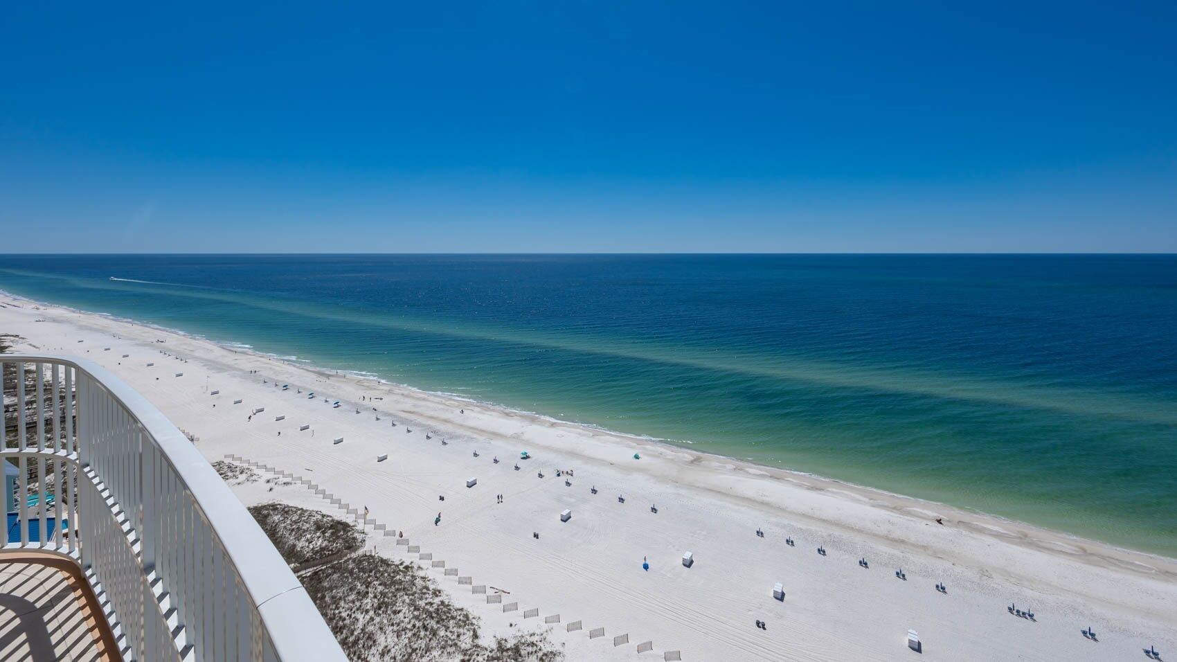 Ein Strand mit freiem Blick auf den Ozean, eine Treppe, die zum Strand hinabführt, und ein Geländer mit Ausblick auf die Szene.