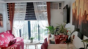 A living room with a sofa, a dining table, and potted plants.