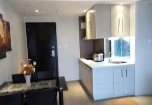 A modern kitchen with white cabinets, a dining table with chairs, and a black door.