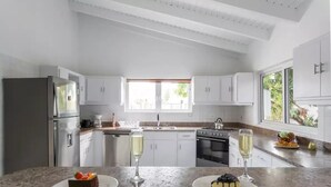 A modern kitchen with white cabinets, a stainless steel refrigerator, and a large window providing natural light. - 3BR 2.5BA Villa w/Pool in Palm Beach (Noord)