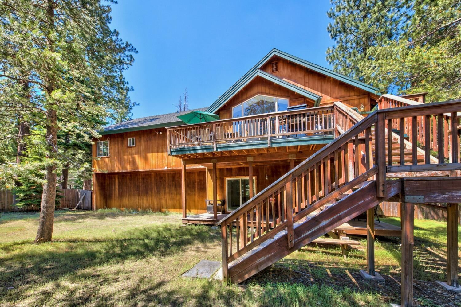 Eine zweistöckige Holzhütte mit Balkon und Terrasse.