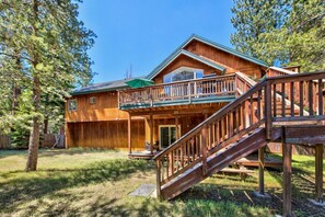 A two-story wooden cabin with a balcony and a deck.