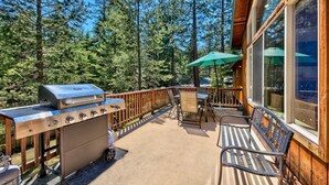 An outdoor patio with a grill, seating, and a view of the forest. - Alpine Family Adventure - Pets, BBQ, Games (South Lake Tahoe)
