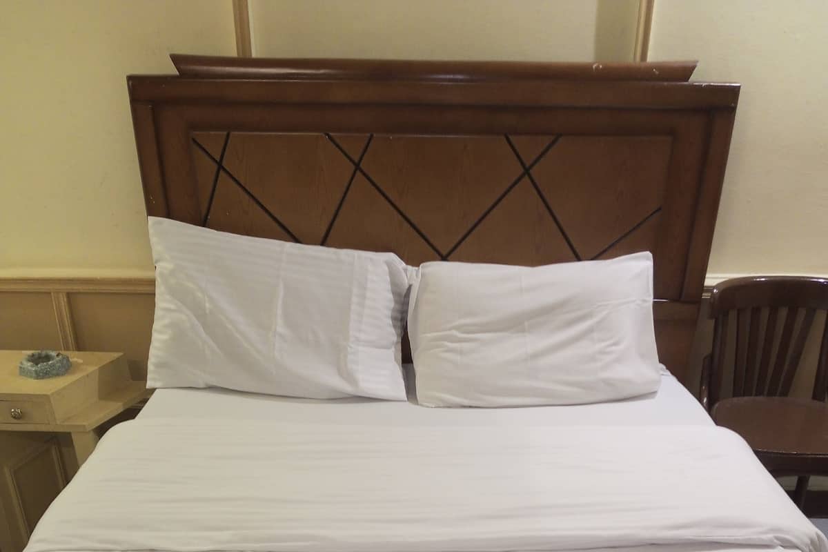 A neatly made bed with white linens and a folded towel on the bed.