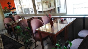 A dining area with a glass table, four chairs, and a view of a building across the street. - Panorama Palace hotel  (Cairo)