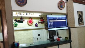 A reception desk with a computer monitor, decorative items, and a wall clock. - Panorama Palace hotel  (Cairo)