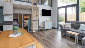 Un intérieur moderne avec une table à manger en bois, un canapé gris et un téléviseur fixé au mur.