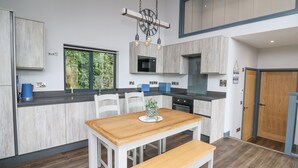 Une cuisine moderne avec une table et un banc en bois, des armoires blanches et une grande fenêtre.