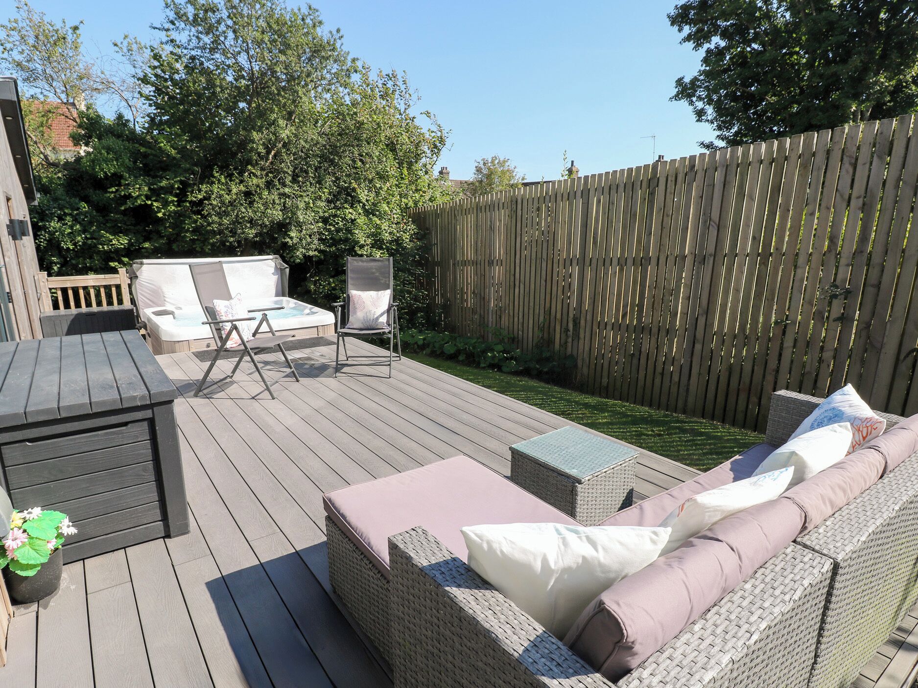 Une terrasse dotée de mobilier d’extérieur, comprenant un canapé et des fauteuils, et un jacuzzi en arrière-plan.