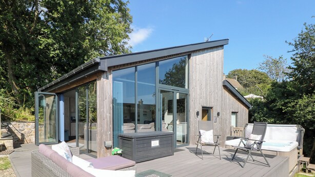 Une maison moderne dotée d’une terrasse, de grandes baies vitrées et d’un espace salon extérieur.