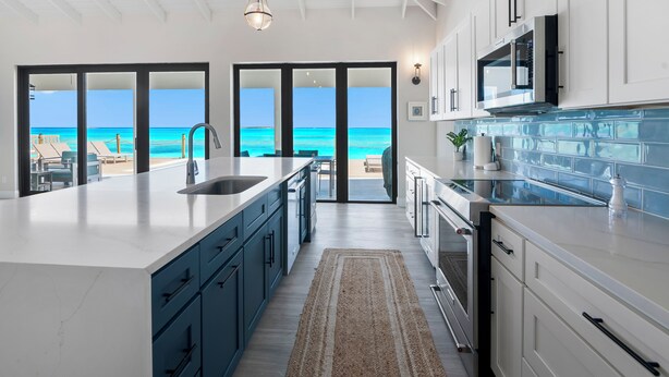 A modern kitchen with a large island, built-in appliances, and a view of the ocean. - "New" 5 bedroom Exuma Beach Front Estate w/ Pool & No Neighbors on either side! (Harts)