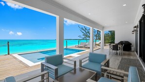 A modern outdoor lounge area with a pool, seating, and a view of the ocean. - "New" 5 bedroom Exuma Beach Front Estate w/ Pool & No Neighbors on either side! (Harts)