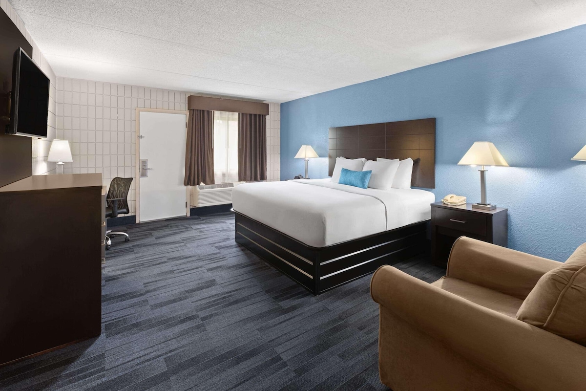 Een hotelkamer met een bed, nachtkastjes, een bureau, een televisie en een stoel.