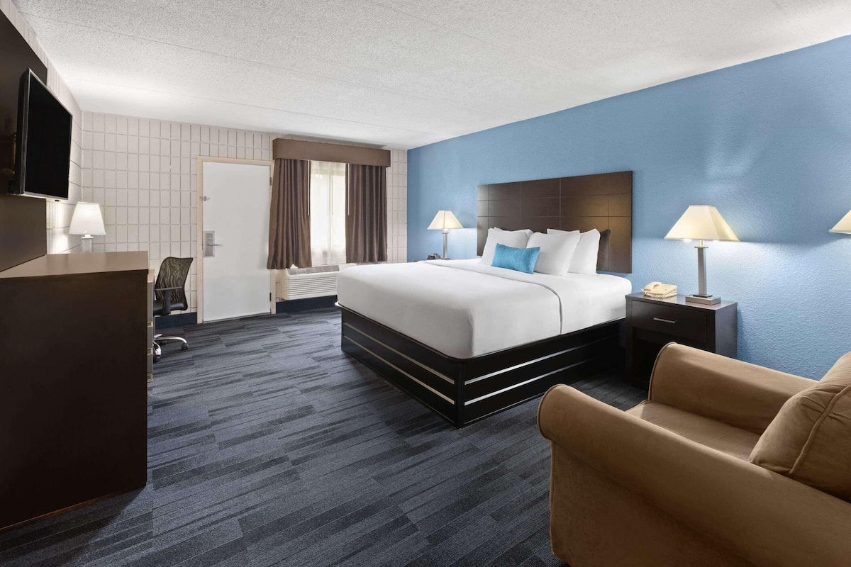Een hotelkamer met een bed, nachtkastjes, een bureau, een televisie en een stoel.