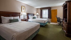 Une chambre d’hôtel avec deux lits, un bureau, une chaise, une armoire et une fenêtre avec des rideaux.