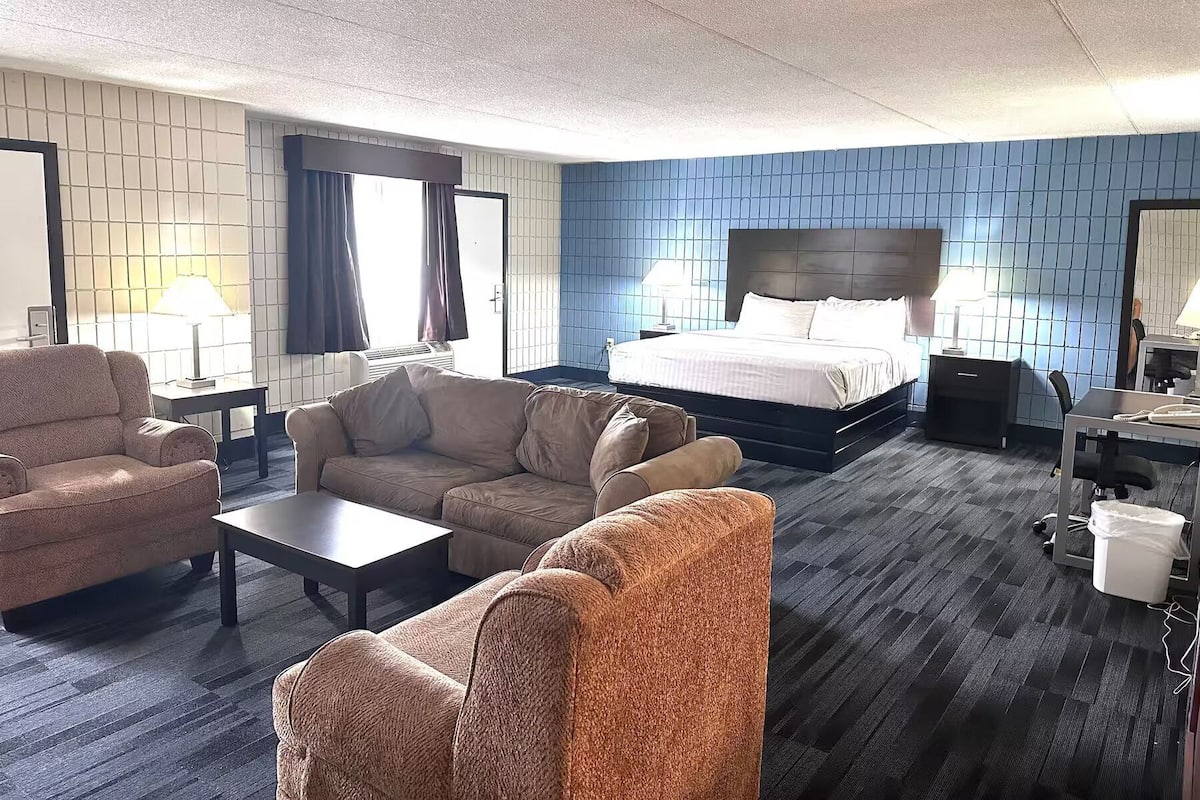 Een hotelkamer met een bed, twee banken, een bureau en een stoel.