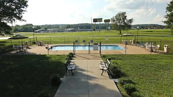 A pool area with a fenced deck, lounge chairs, and a pathway leading to the pool.