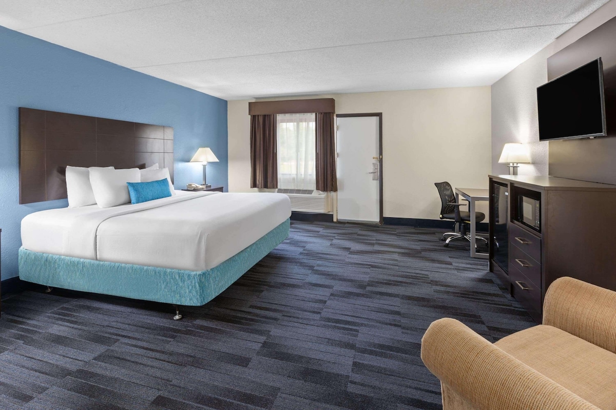 Een hotelkamer met een bed, bureau, stoel, televisie en een deur.