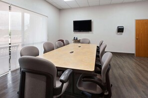 A conference room with a large table, chairs, a TV, and a door.