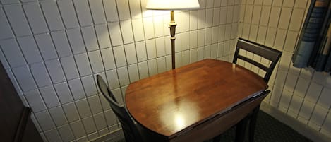Un pequeño comedor con una mesa, sillas, una lámpara y un muro con azulejos.