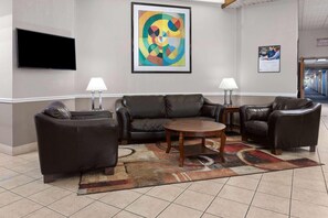 A lobby with a sofa set, a coffee table, two lamps, a TV, and a colorful abstract painting.