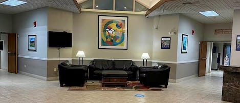 Un vestíbulo con techo alto, un cuadro grande, un conjunto de sofás y una mesa de recepción.