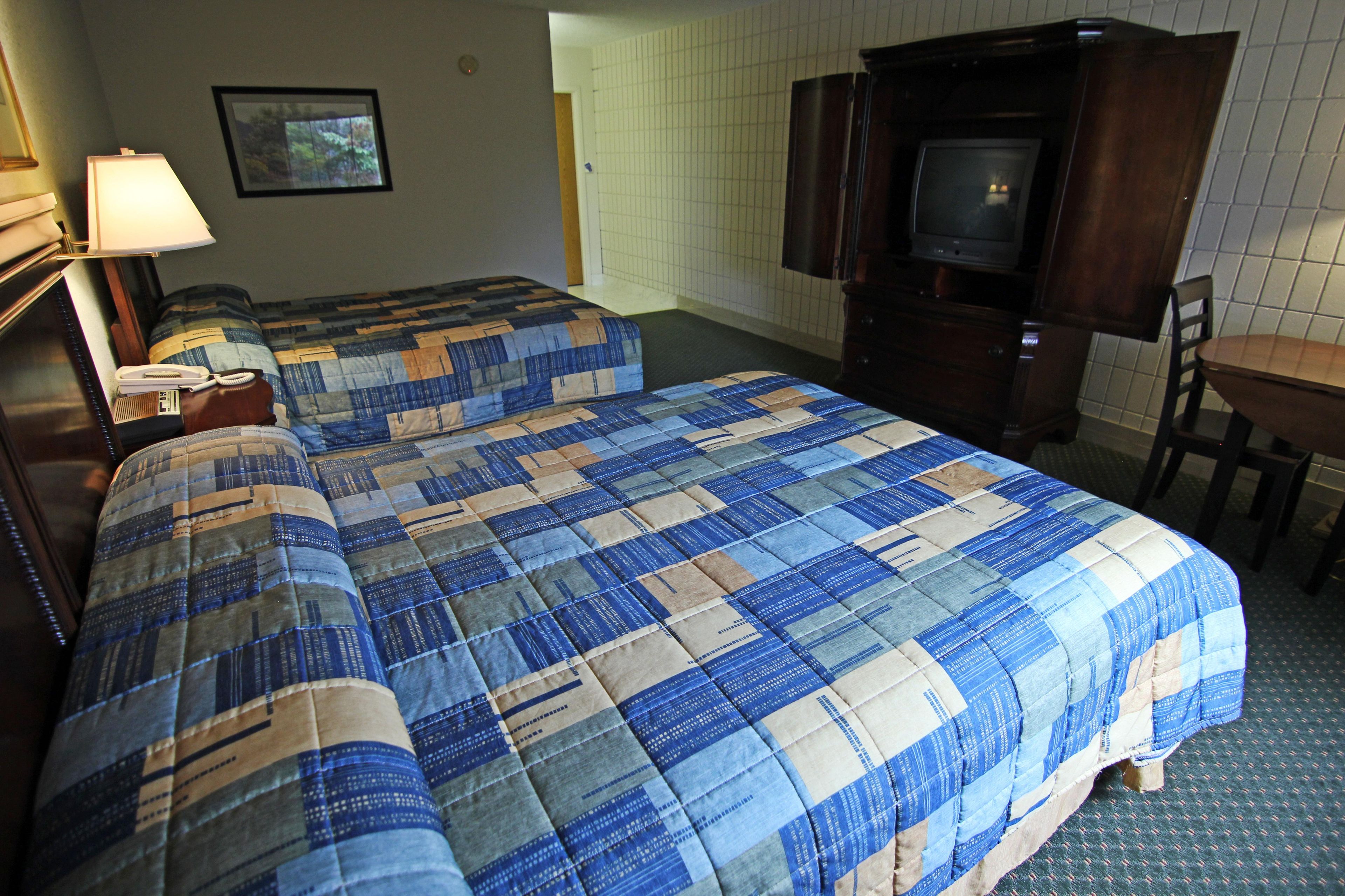 Een hotelkamer met twee bedden, een bureau, een televisie en een telefoon.