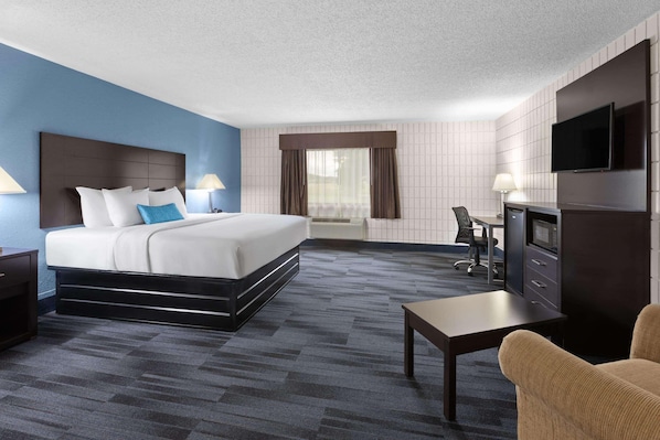 Ein Hotelzimmer mit Bett, Schreibtisch, Fernseher und Blick ins Freie.